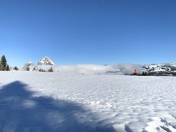 Snow covered landscape against blue sky