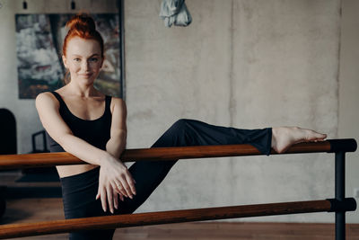 Portrait of woman with leg on railing at gym