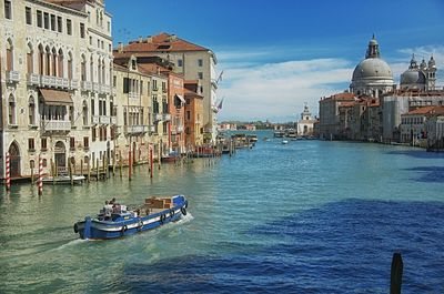 People on motorboat in canal with santa maria della salute against sky