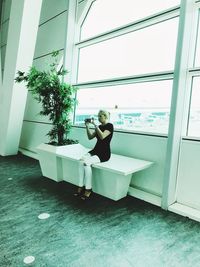 Woman sitting on window at home