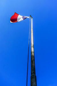 Low angle view of flag against clear blue sky