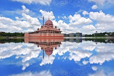 Reflection of building in lake against cloudy sky