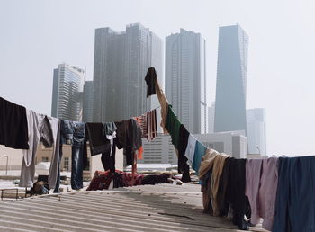 Clothes drying against modern buildings in city against sky
