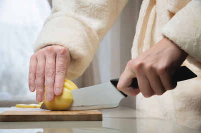 Close-up of female hands cutting peeled potatoes on a wooden cutting board. home cooking potatoes