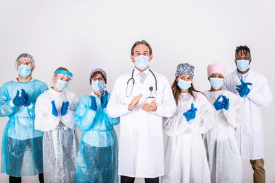 Portrait of doctors wearing mask standing against white background