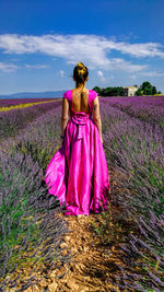 Rear view of woman standing on field against sky