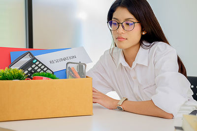 Woman with objects sitting at desk in office