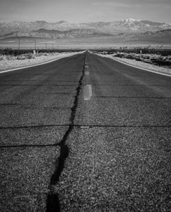 Cracked road leading towards mountains