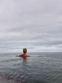 Rear view of man in sea against sky