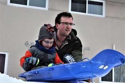 Father and son with tobogganing on snow during winter