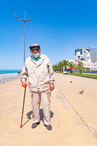 Full length portrait of man standing against blue sea
