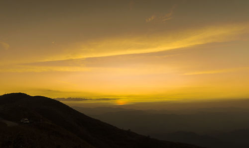 Scenic view of silhouette mountains against orange sky