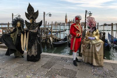 Couples wearing costumes while standing on promenade in city against sky