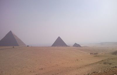 Pyramids in desert against clear sky on sunny day