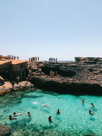 People swimming in sea against clear sky