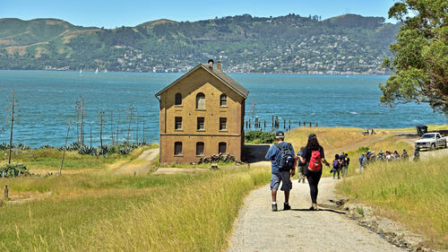 People walking on shore by sea against sky