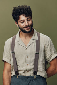 Portrait of young man standing against green background