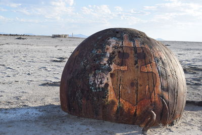 Close-up of rusty metal on beach against sky