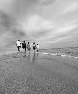 Rear view of people on beach against sky