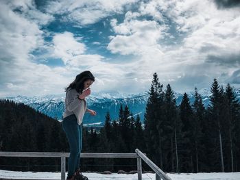 Man standing by plants against sky during winter