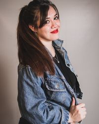 Smiling young woman standing against wall