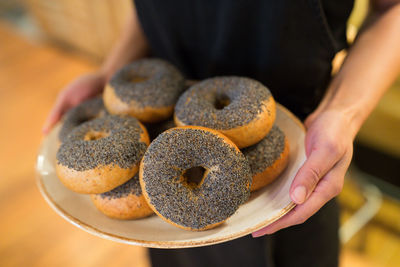 Midsection of woman holding bagels in plate