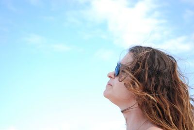 Side view of young woman against sky