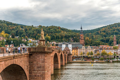 Arch bridge over river against buildings in city