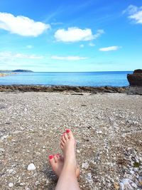 Low section of person on beach against sky