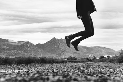 Low section of man jumping against mountain