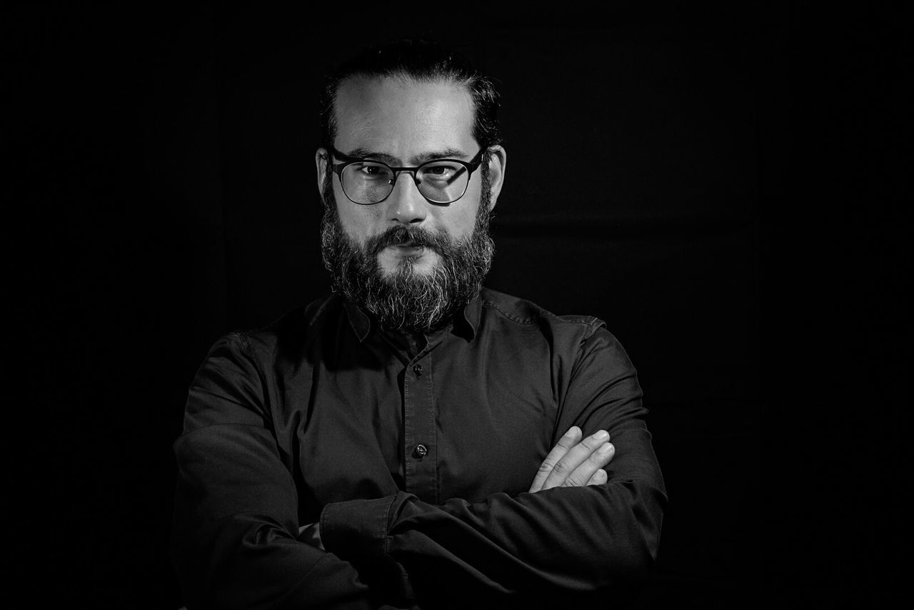 facial hair, beard, front view, one person, glasses, eyeglasses, indoors, black background, males, mid adult men, men, young men, adult, lifestyles, mid adult, real people, studio shot, waist up, mature men, dark, serious, mustache, contemplation