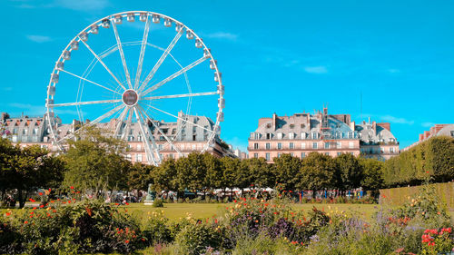 Ferris wheel in city against blue sky