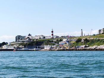 Sea by buildings against clear sky