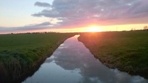 Scenic view of agricultural landscape against sky during sunset