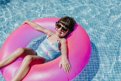 High angle portrait of smiling relaxing on inflatable ring in swimming pool