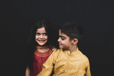 Smiling siblings against black background