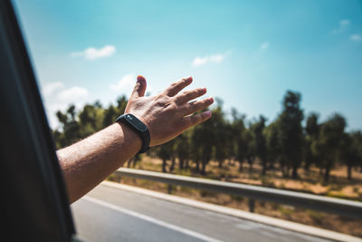 Midsection of man skateboarding on road against sky