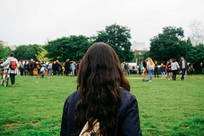 Rear view of woman standing on grassy field at park