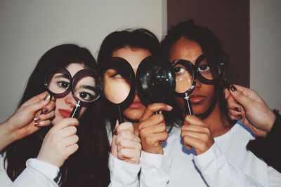 Close-up of young friends looking through magnifying glass