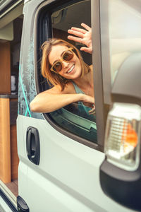 Portrait of smiling woman gesturing while sitting in van