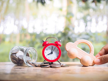 Cropped hand of woman holding alarm clock on table