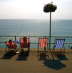 Chairs and table at beach against clear sky