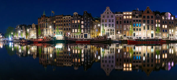 Boats moored in canal by buildings against sky in city at night