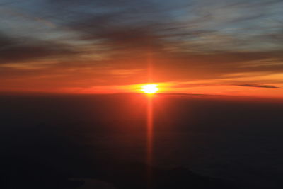 Sun shining through clouds over sea