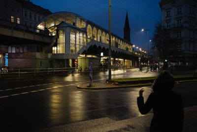 Man walking on street against illuminated buildings at night