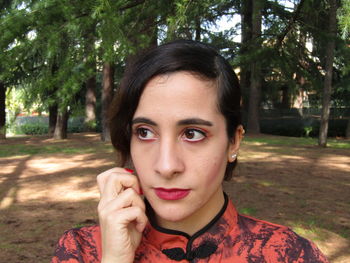 Close-up portrait of young woman against trees