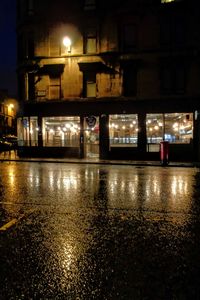 Reflection of illuminated building in puddle at night