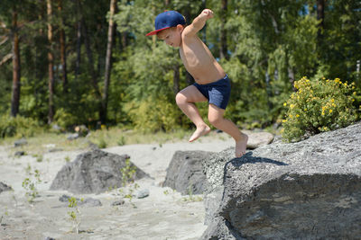 Full length of shirtless boy on jumping on rock