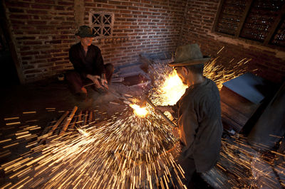 High angle view of coworkers welding metal in workshop