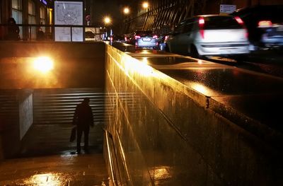 Woman standing on illuminated street at night